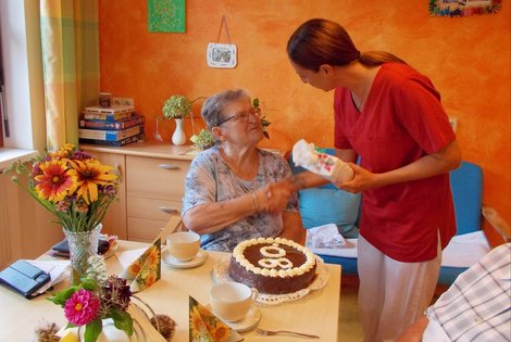 Pflegerin gratuliert zum 80.Geburtstag und überreicht Geschenk