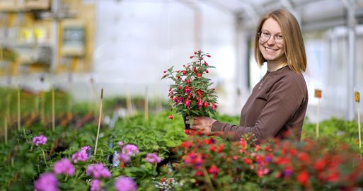 Gärtnerin umgeben von Pflanzen im Glasgarten