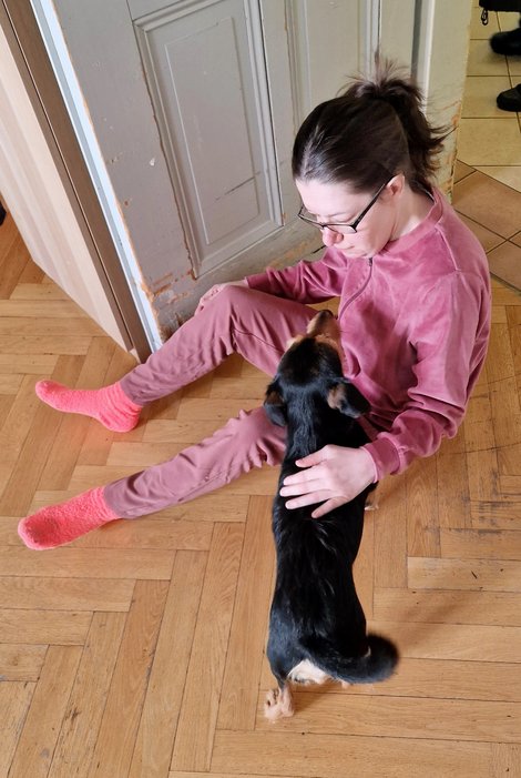 Bewohnerin sitzt am Boden mit Therapiehund Pluto