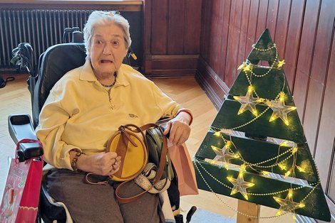 Bewohnerin beim Adventsingen neben Christbaum