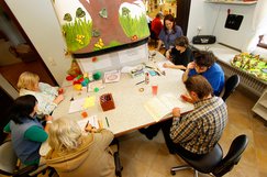 Bewohnerinnen und Bewohner sitzen gemeinsam an einem Tisch in der Kreativwerkstatt.