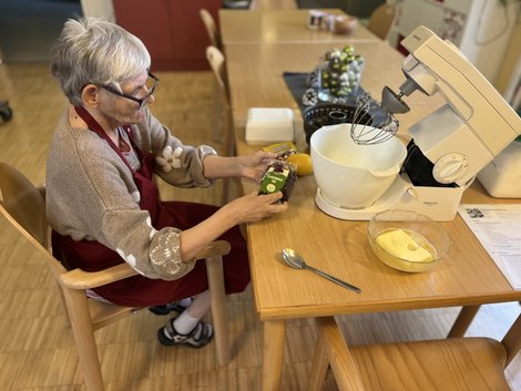 Bewohnerin Annemarie sitzt bei Tisch, vor ihr Küchenmaschine.