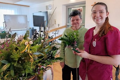 Ergotherapeutin Verena Poinstingl mit Bewohnerin und vielen Palmbesen